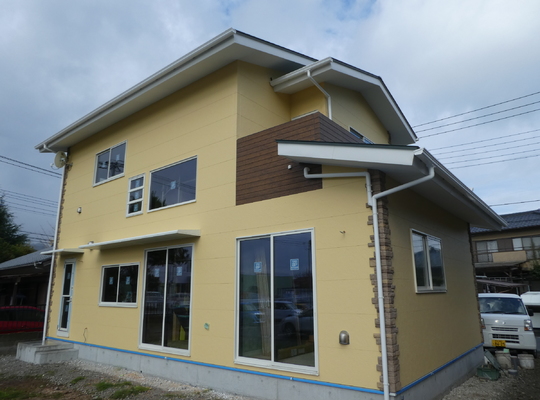 黄色い外壁と緑の屋根の新築住宅