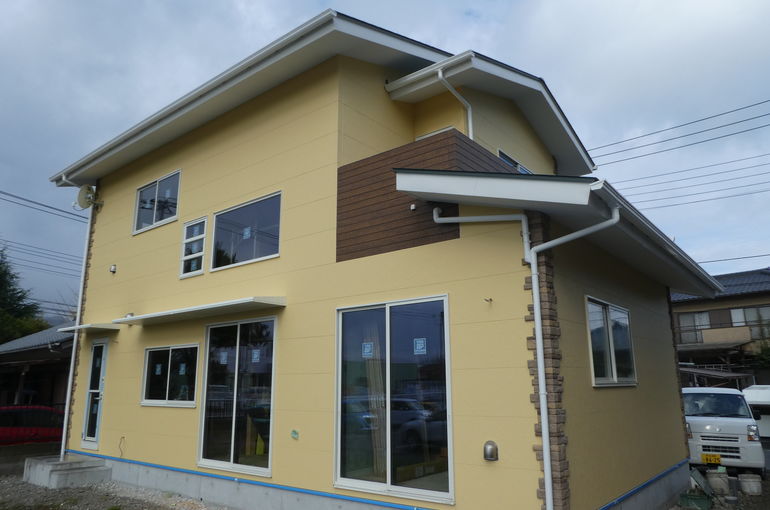 黄色い外壁と緑の屋根の新築住宅